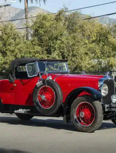 Stutz Model BB Custom Black Hawk Two-Passenger Speedster von 1928 in Rot und Schwarz auf einer Straße, Cabriolet-Verdeck und klassische Speichenräder.