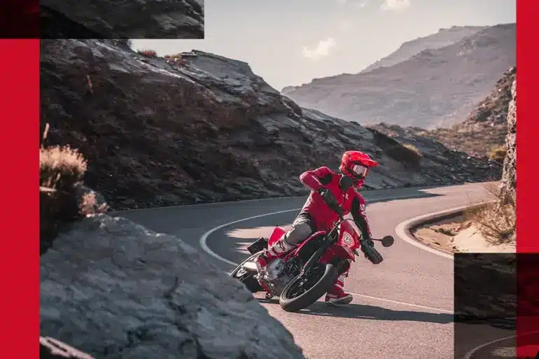 Motorradfahrer auf roter GasGas SM 700 2024 beim sportlichen Fahren auf einer kurvigen Bergstraße.