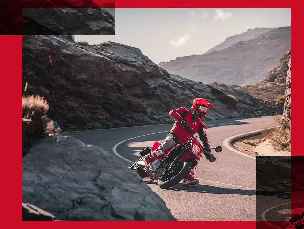 Motorradfahrer auf roter GasGas SM 700 2024 beim sportlichen Fahren auf einer kurvigen Bergstraße.