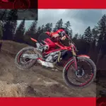 GASGAS TXT GP 250 2025 Trial-Motorrad im Sprung im Gelände, Fahrer mit roter Ausrüstung, Wald im Hintergrund.