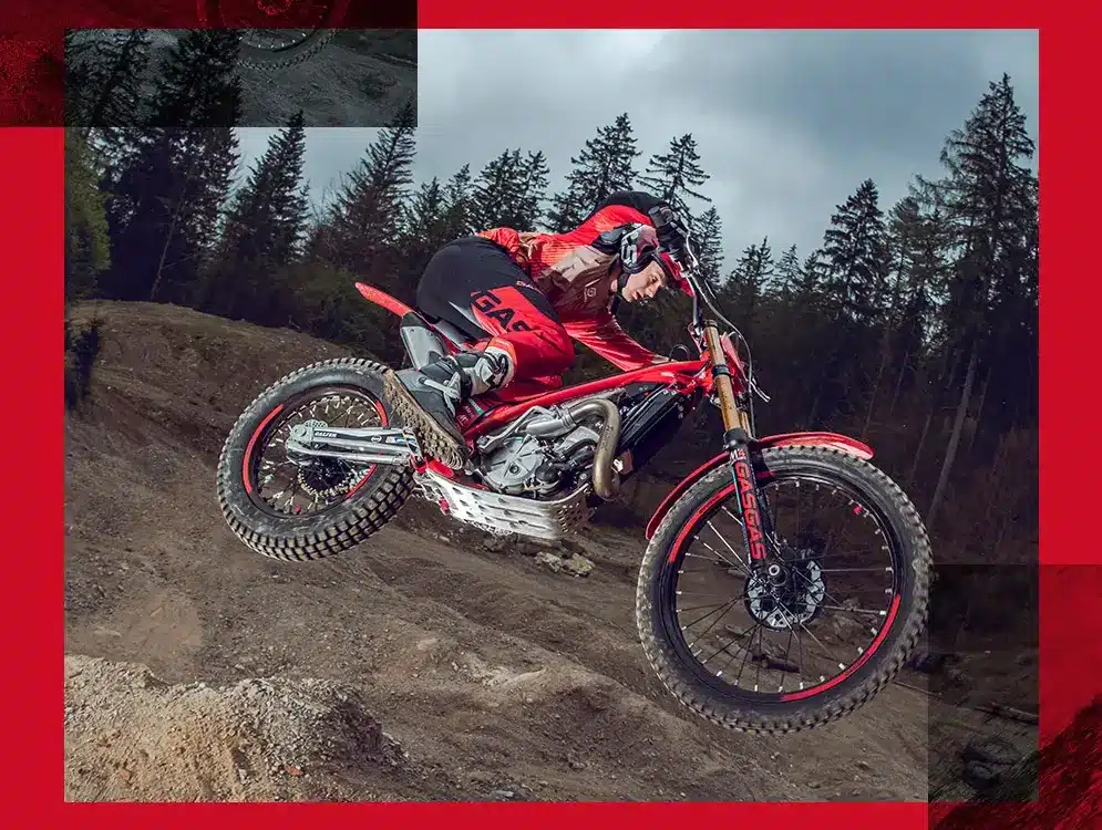 GASGAS TXT GP 250 2025 Trial-Motorrad im Sprung im Gelände, Fahrer mit roter Ausrüstung, Wald im Hintergrund.