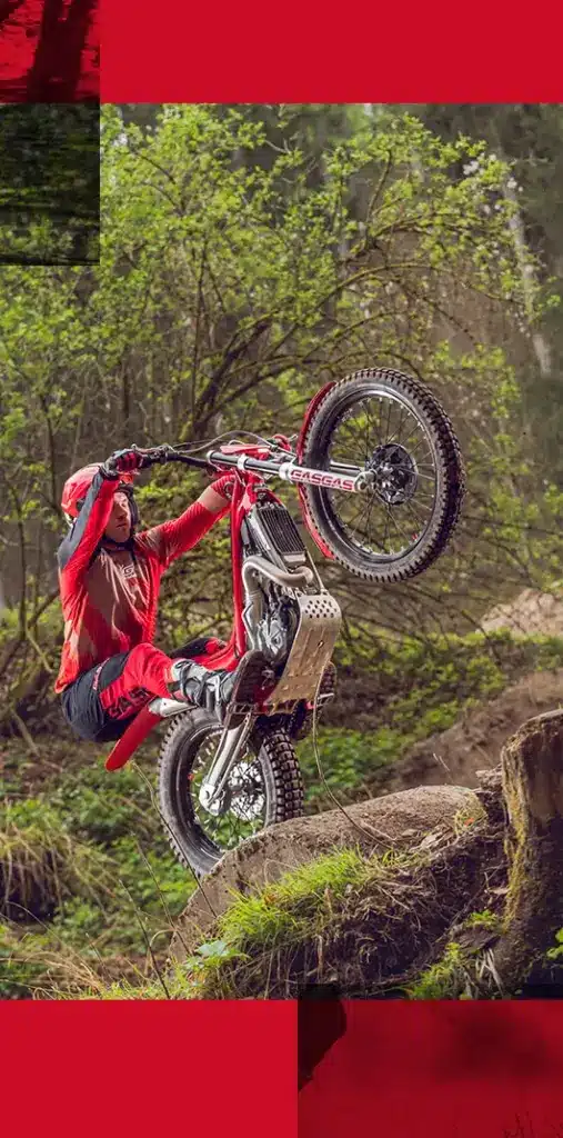 Trialfahrer auf einer GasGas TXT RACING 300 2025 überwindet einen Felsen im bewaldeten Terrain.
