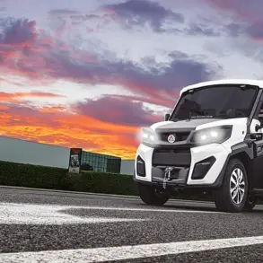 Alkè ATX Elektro-Nutzfahrzeug fährt über eine Straße vor farbigem Himmel.