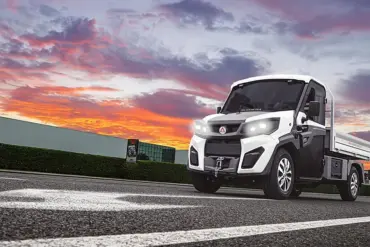 Alkè ATX Elektro-Nutzfahrzeug fährt über eine Straße vor farbigem Himmel.