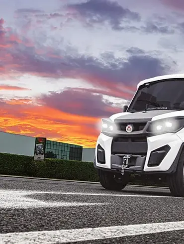 Alkè ATX Elektro-Nutzfahrzeug fährt über eine Straße vor farbigem Himmel.