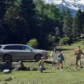 Familie vor einem silbernen Li L9 SUV in einer Waldlandschaft mit Bergen im Hintergrund.