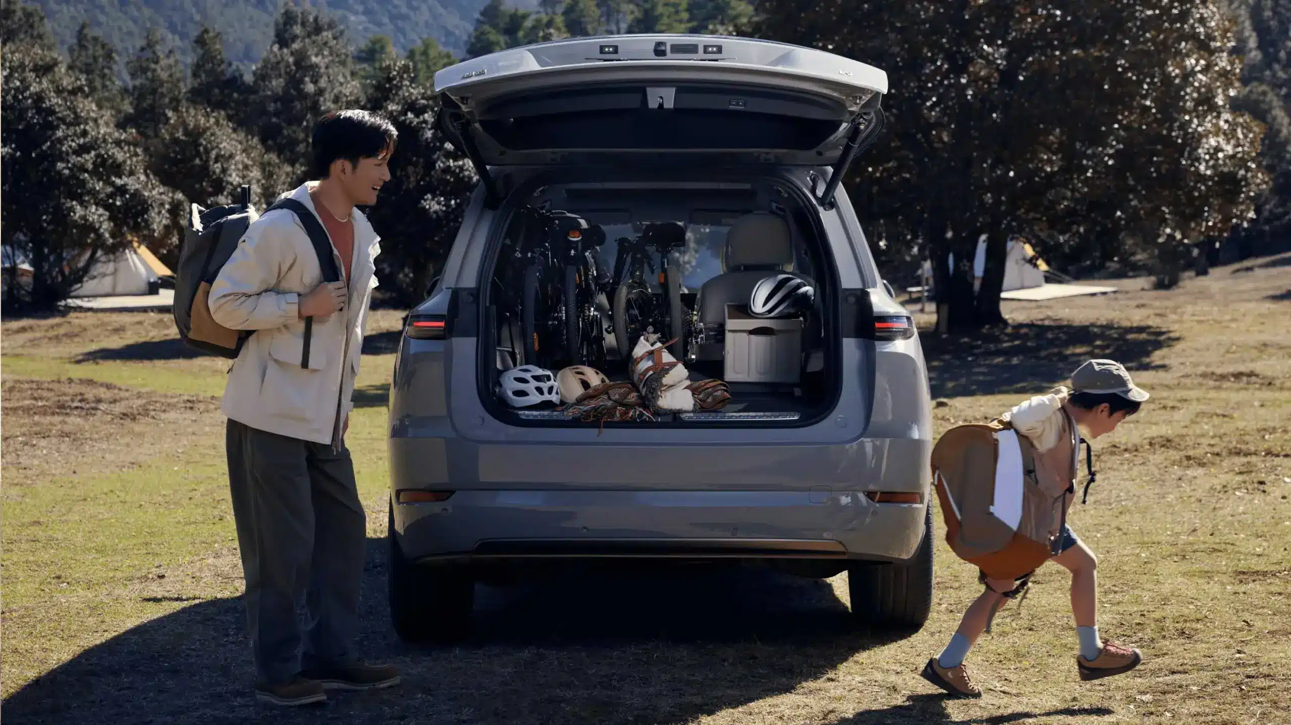 Offener Kofferraum eines Li L9 SUV, bepackt mit Fahrrädern, Helmen und Outdoor-Ausrüstung, Vater und Kind beim Ausladen.