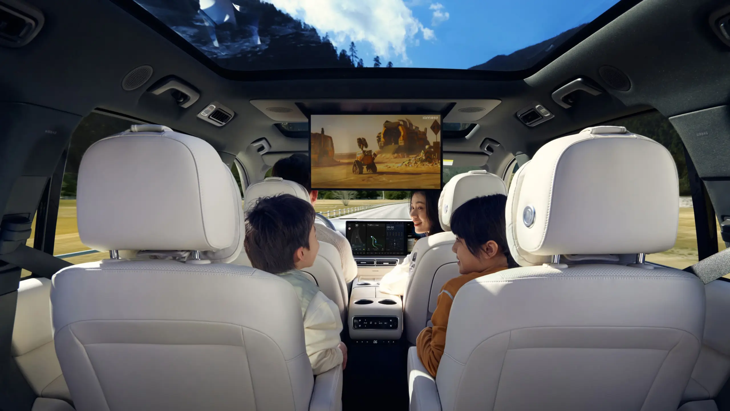Blick auf den luxuriösen Innenraum eines Li L9 mit sechs Einzelsitzen, großem Panoramadach und Bord-Entertainment auf einem Bildschirm während der Fahrt.