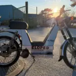 Seitenansicht eines Berix Eloped Elektromopeds aus den 1980er-Jahren, aufgenommen im Außenbereich bei Sonnenuntergang.