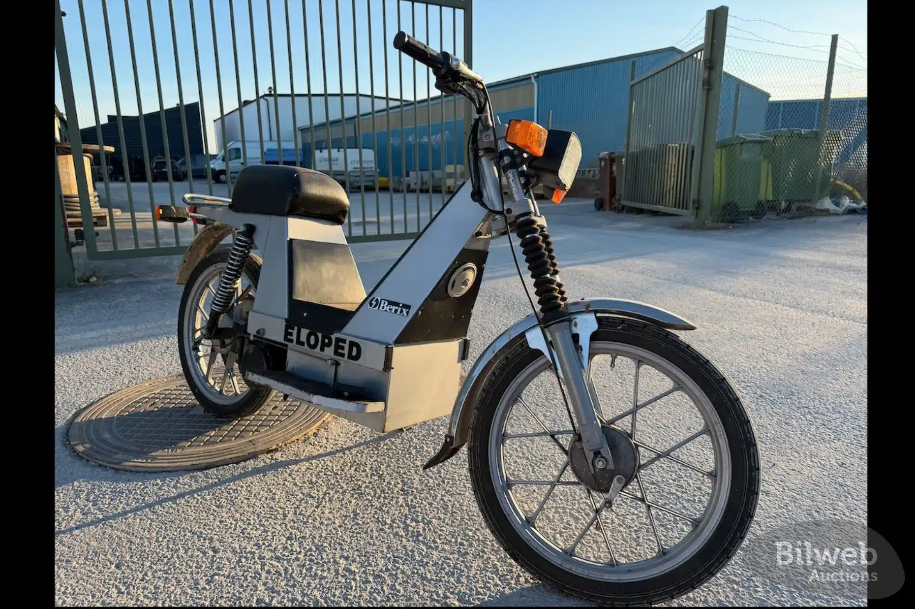 Berix Eloped Elektromoped, Baujahr 1980er, stehend vor einem Metalltor auf Asphalt.