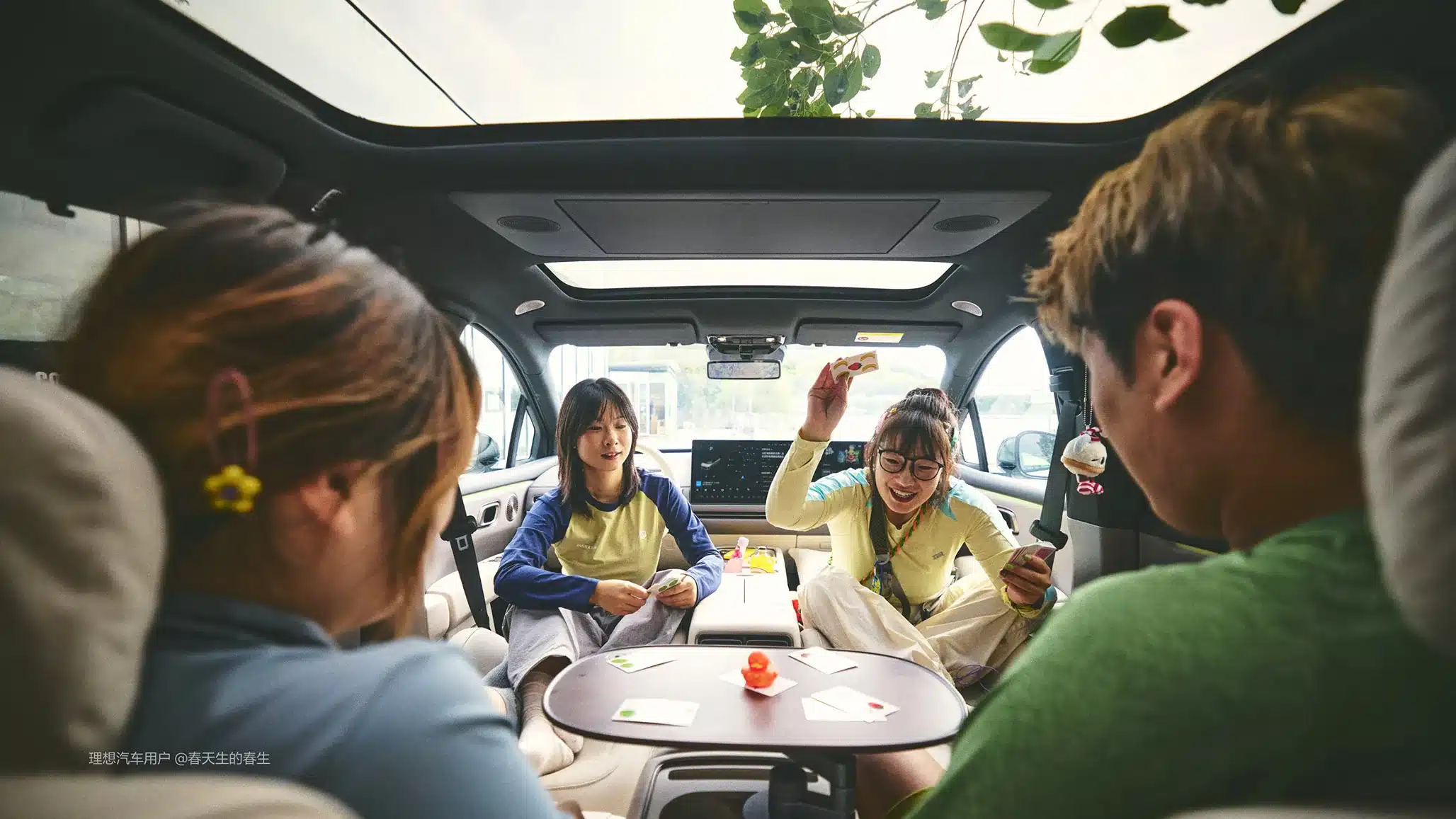 Innenraum des Li Auto i6 mit vier Personen, die unter einem Panoramadach Karten spielen.