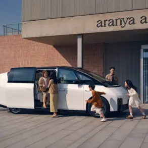 Weißer Li MEGA Elektro-Van mit geöffneter Schiebetür, mehrere Menschen verschiedener Generationen steigen ein und aus, modernes Gebäude im Hintergrund.