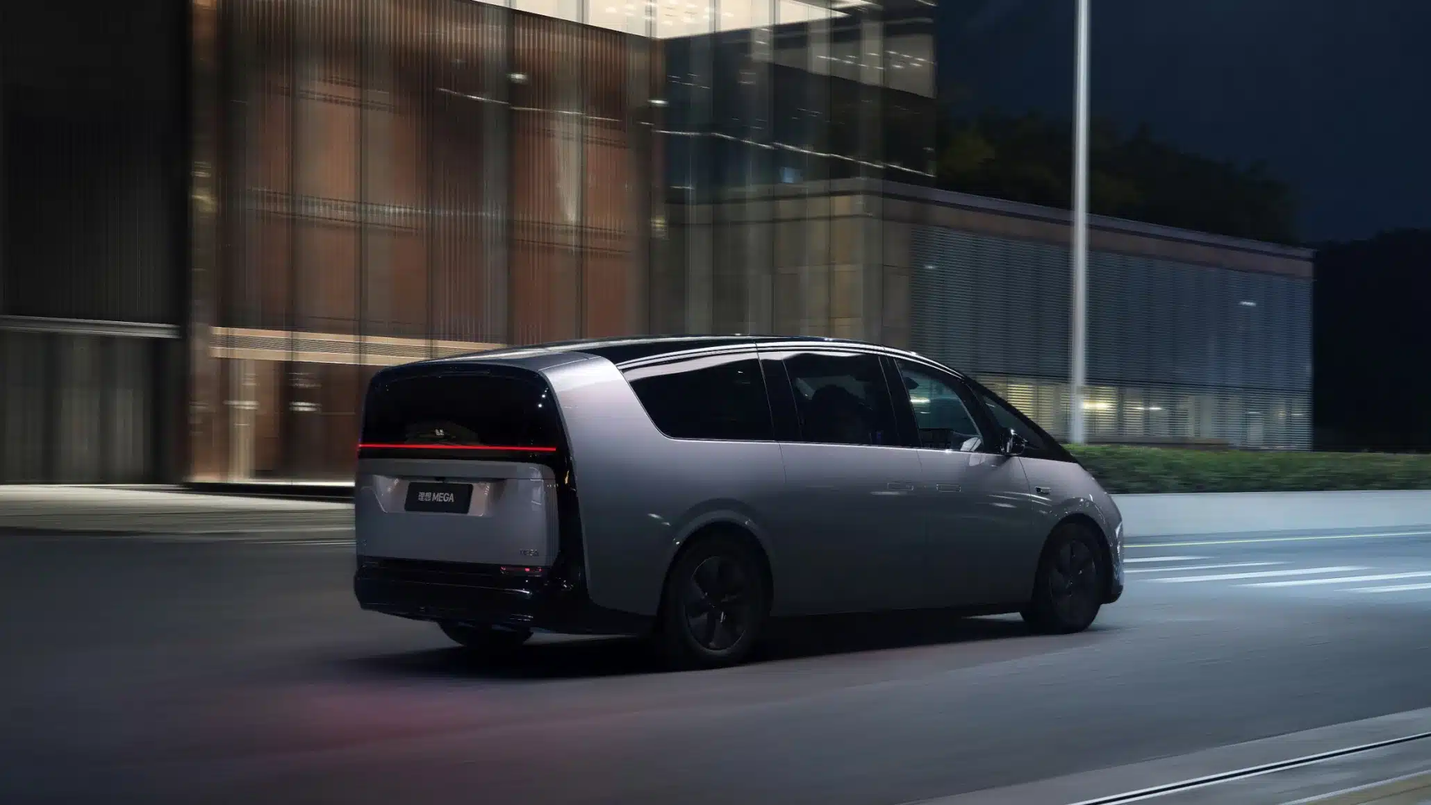 Heckansicht des Li MEGA Elektro-Vans bei Nachtfahrt vor moderner Gebäude-Kulisse