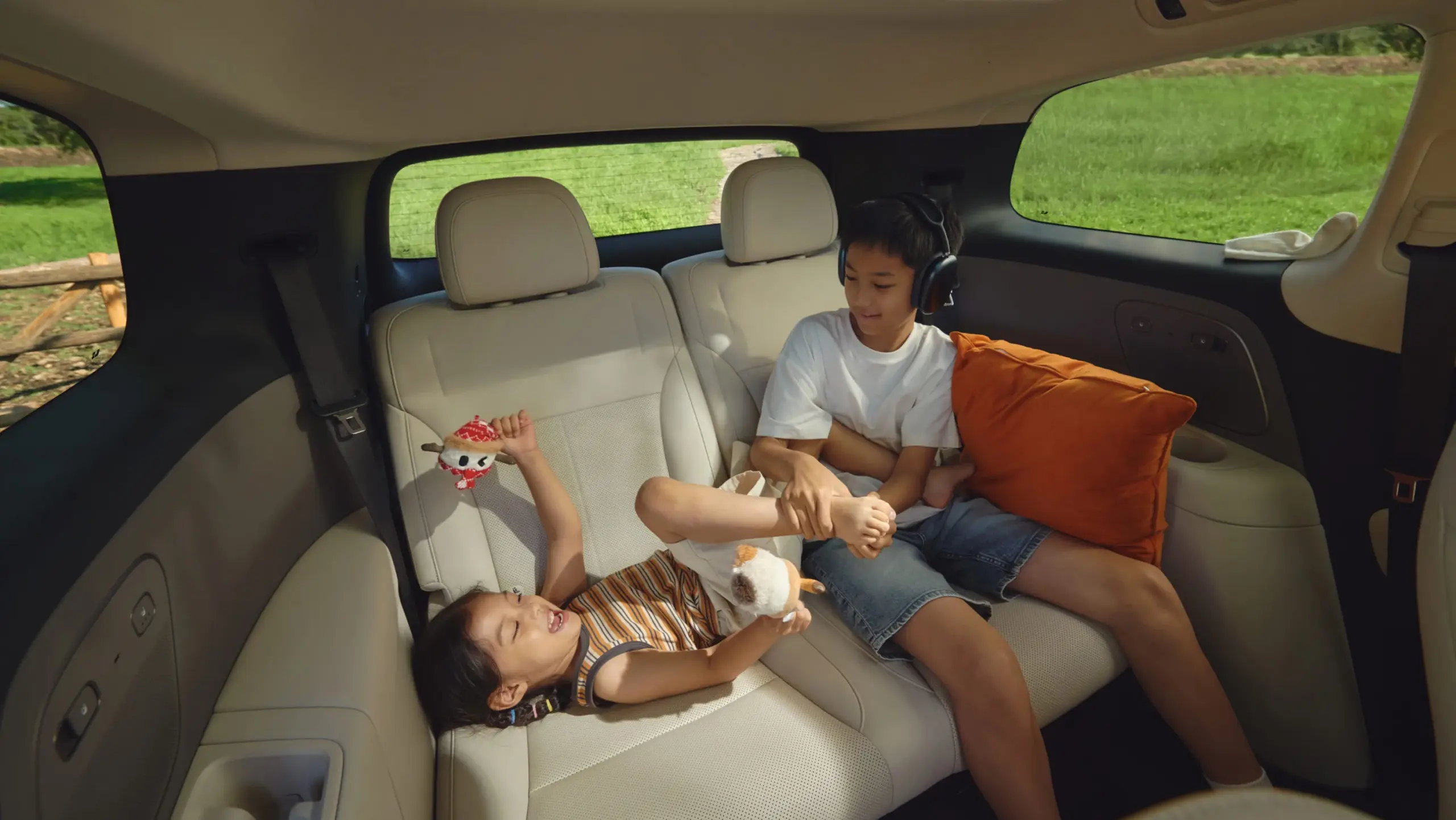 Zwei Kinder sitzen und spielen auf der hellen Rückbank eines Li Auto i8 in einer ländlichen Umgebung