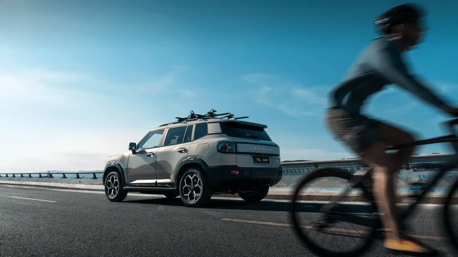 Jetour T1 i-DM Plug-in-Hybrid SUV in Seitenansicht auf einer Straße mit Radfahrer im Vordergrund