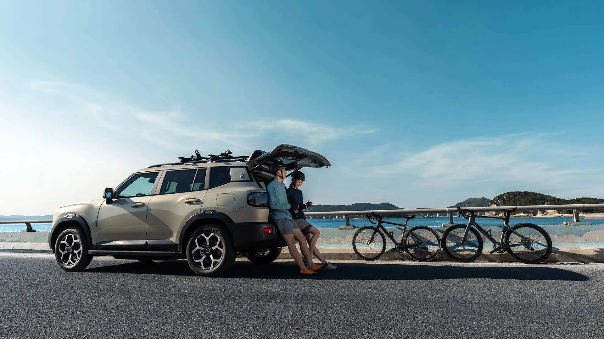 Jetour T1 i-DM Plug-in-Hybrid SUV mit geöffneter Heckklappe und zwei Fahrrädern am Meer