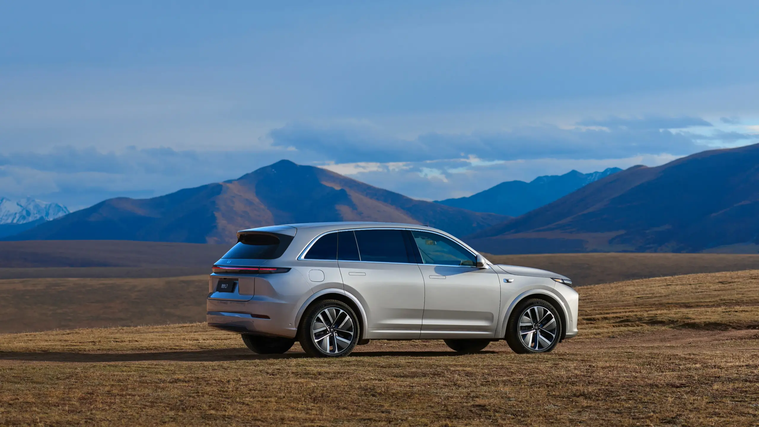 Li L7 SUV seitlich in einer offenen Landschaft mit Bergen im Hintergrund