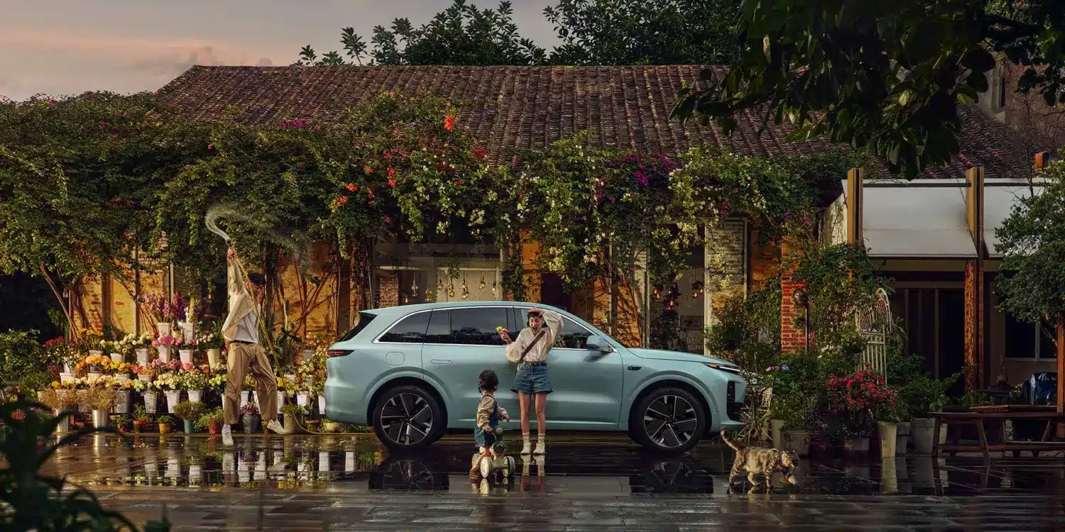 Li L6 SUV in hellblauer Lackierung, geparkt vor einem Blumenladen mit Familie und Katze im Vordergrund.