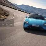 Xiaomi SU7 Max in Gulf Blue fährt dynamisch auf einer Gebirgsstraße, Frontansicht mit Leistungsdaten eingeblendet.