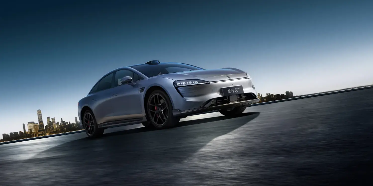 Zhijie S7 Elektroauto sportlich dynamisch auf offener Strecke vor Skyline bei Sonnenaufgang
