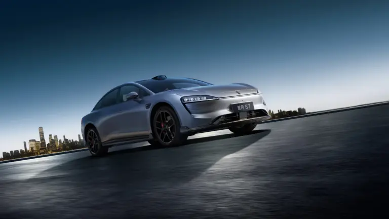 Zhijie S7 Elektroauto sportlich dynamisch auf offener Strecke vor Skyline bei Sonnenaufgang