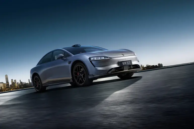 Zhijie S7 Elektroauto sportlich dynamisch auf offener Strecke vor Skyline bei Sonnenaufgang