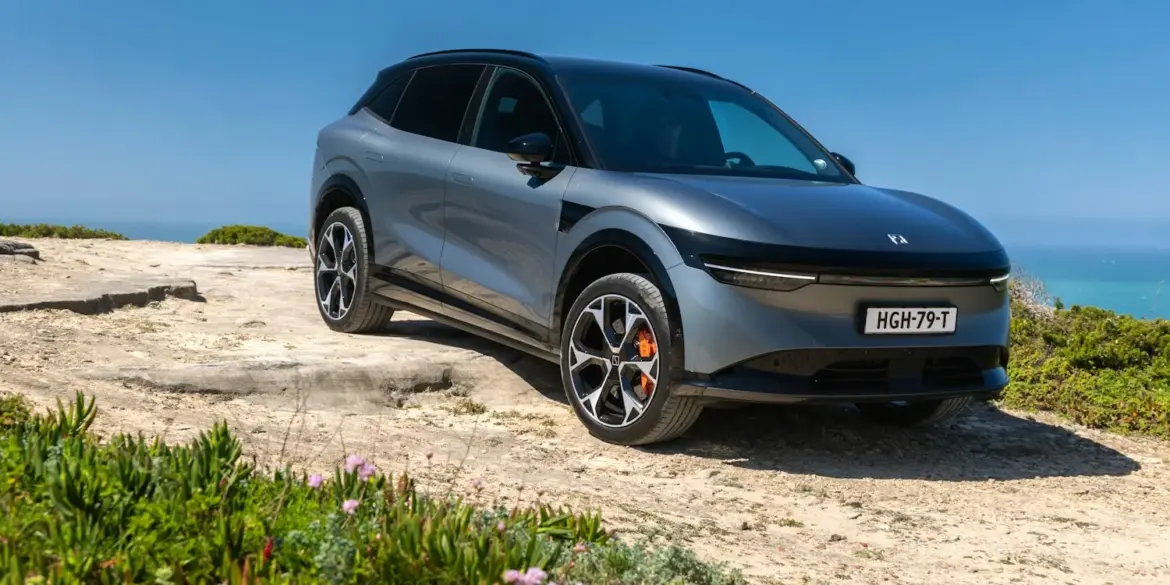 Silberner Zeekr 7X SUV geparkt auf einer Felsklippe mit Blick aufs Meer unter blauem Himmel.