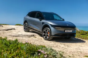 Silberner Zeekr 7X SUV geparkt auf einer Felsklippe mit Blick aufs Meer unter blauem Himmel.