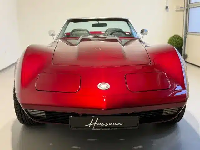 Chevrolet Corvette C3 Cabriolet in roter Candy-Lackierung, frontal aufgenommen, im Showroom
