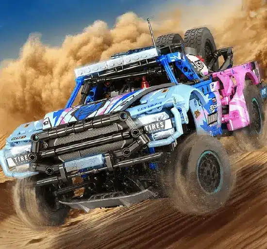 Klemmbausteinmodell eines Dakar Trophy Trucks fährt mit aufwirbelndem Sand dynamisch durch eine Wüstenlandschaft.