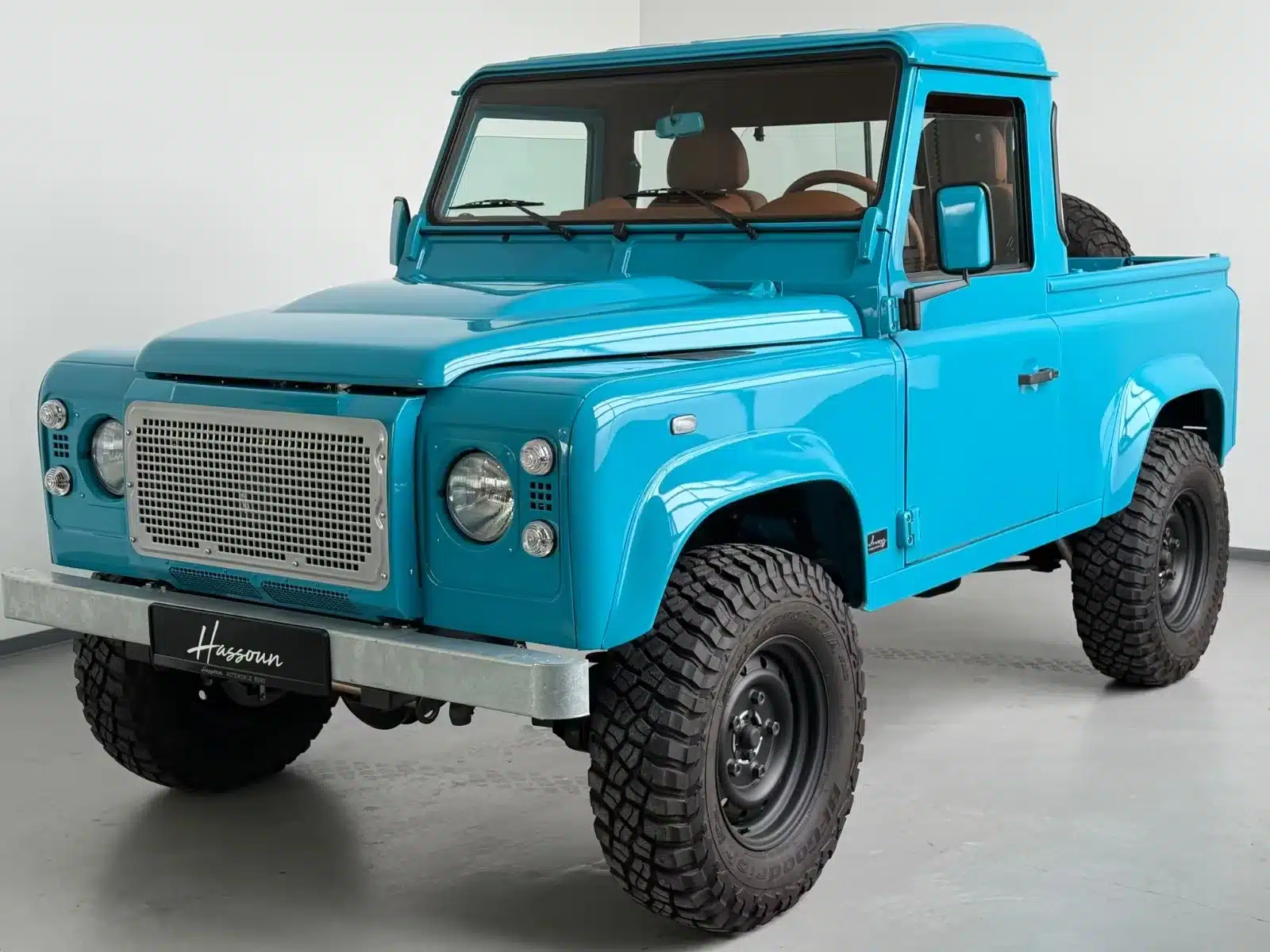 Ein himmelblauer Land Rover Defender TD4, Einzelstück Alvarez One-of-One Showcar Monaco, fotografiert in einer hellen Halle.