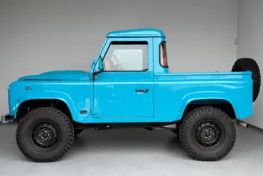 Seitliche Ansicht des Alvarez One-of-One Showcar Monaco, ein blauer Land Rover Defender TD4 Einzelstück, frisch aufgebaut mit Offroad-Bereifung.