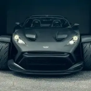Frontansicht des Donkervoort F22 Bare Naked mit blanker Carbonfaser-Karosserie vor einer Industriehalle.