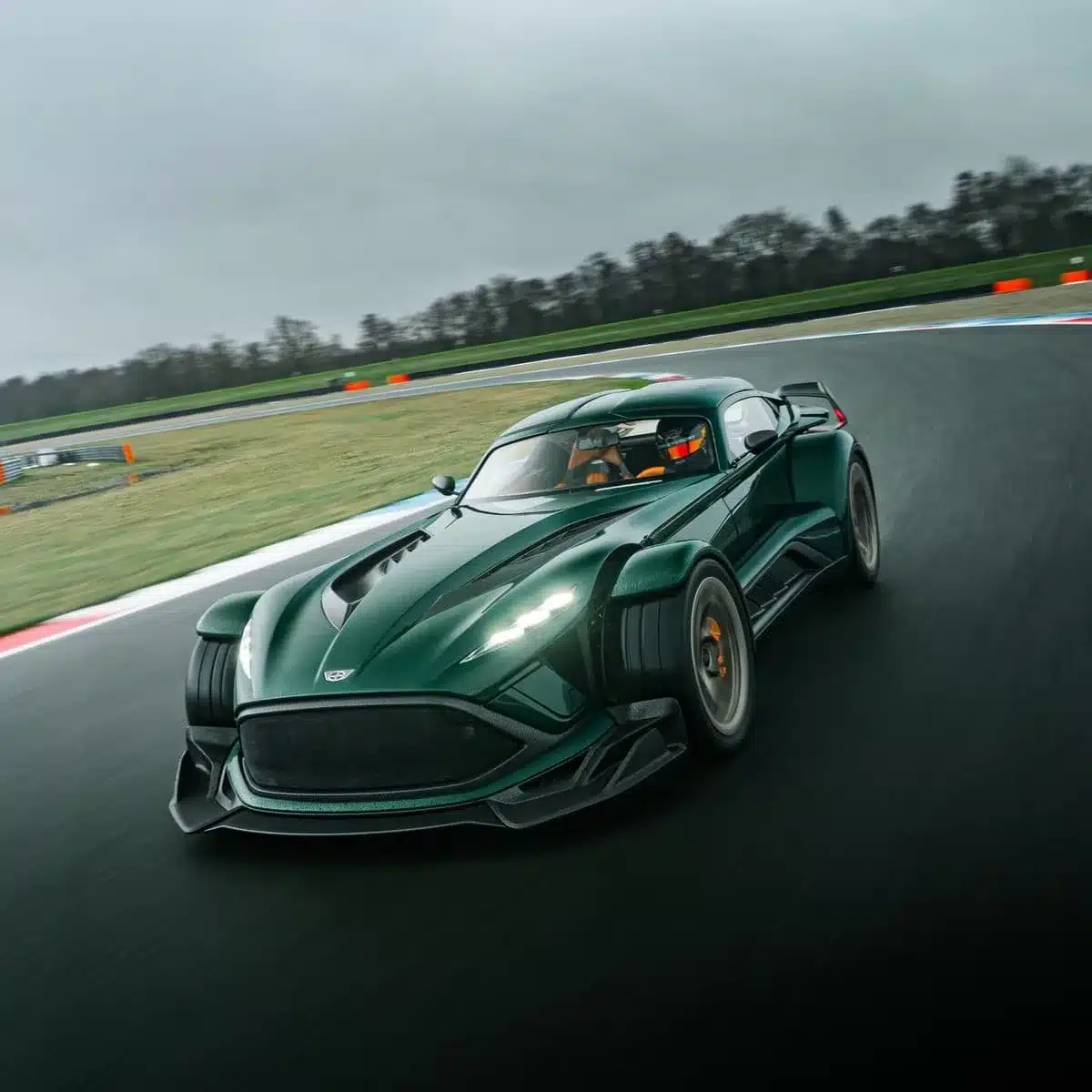 Donkervoort P24 RS in dunkelgrün fährt dynamisch über eine Rennstrecke bei bewölktem Wetter.