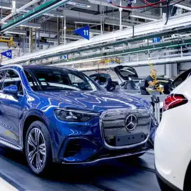 Fertigung des elektrischen Mercedes GLC in einer Produktionshalle in Bremen mit Mitarbeiterin am Fahrzeug.
