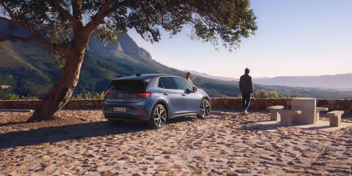 VW ID.3 Neo steht unter einem Baum mit Berglandschaft im Hintergrund