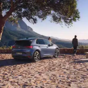VW ID.3 Neo steht unter einem Baum mit Berglandschaft im Hintergrund