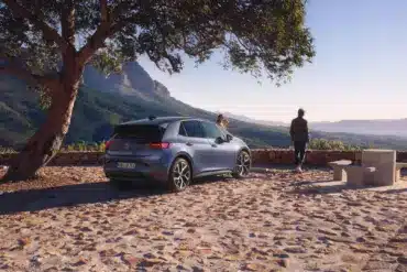 VW ID.3 Neo steht unter einem Baum mit Berglandschaft im Hintergrund