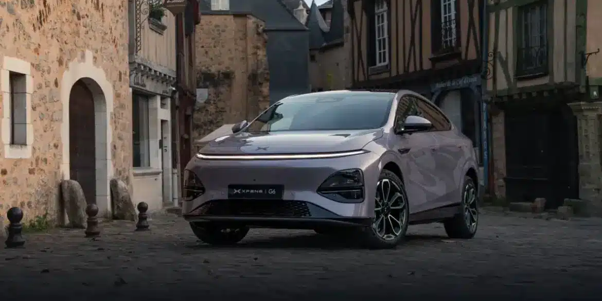 XPENG G6 Elektro-SUV in Metallic-Lackierung steht auf Kopfsteinpflaster vor alten Häusern.