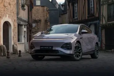 XPENG G6 Elektro-SUV in Metallic-Lackierung steht auf Kopfsteinpflaster vor alten Häusern.