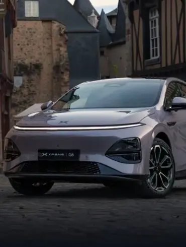 XPENG G6 Elektro-SUV in Metallic-Lackierung steht auf Kopfsteinpflaster vor alten Häusern.