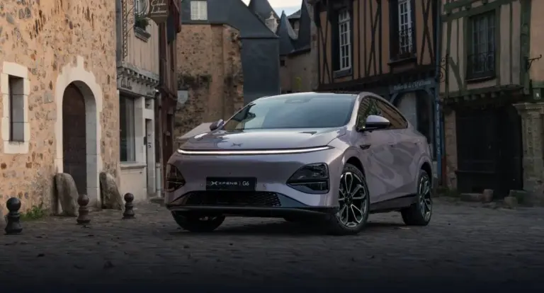 XPENG G6 Elektro-SUV in Metallic-Lackierung steht auf Kopfsteinpflaster vor alten Häusern.