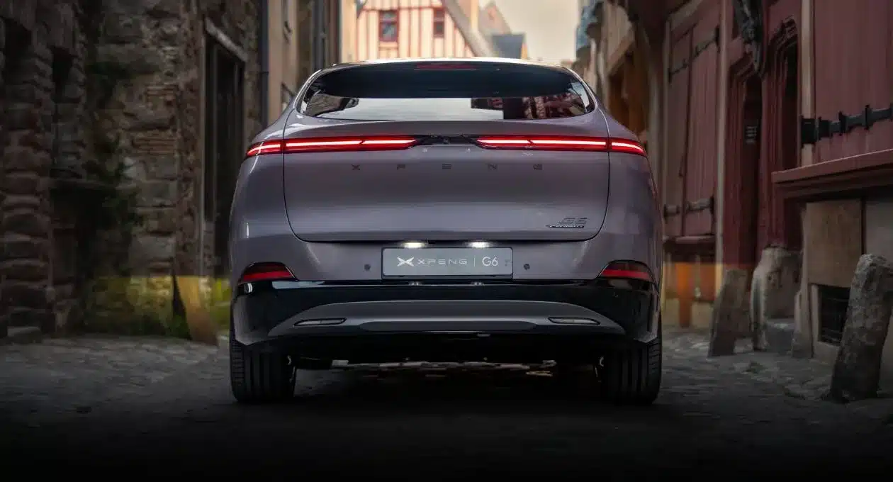 Heckansicht des XPENG G6 Elektro-SUV mit durchgehendem LED-Leuchtenband in einer historischen Gasse
