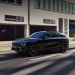 Schwarzer XPENG G9 SUV fährt auf einer sonnigen Straße vor Bürogebäuden.