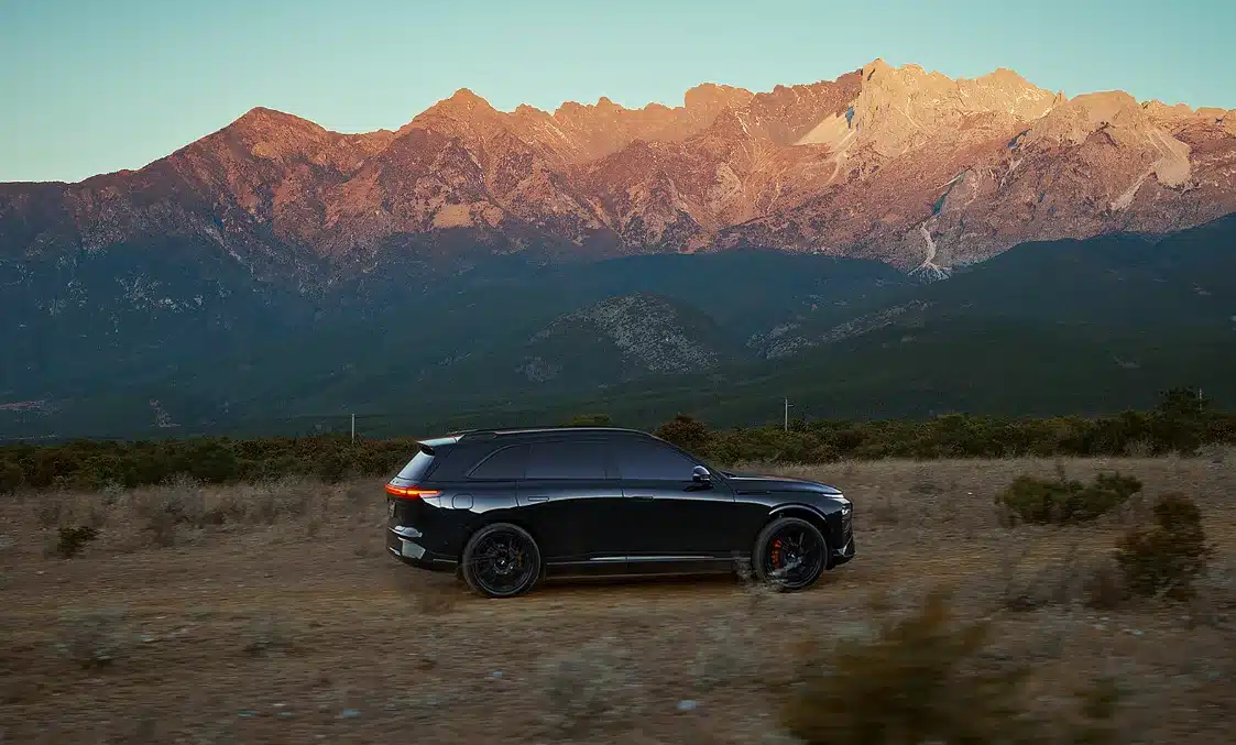 Schwarzer XPENG G9 Black Edition fährt vor einer Bergkulisse auf unbefestigtem Weg