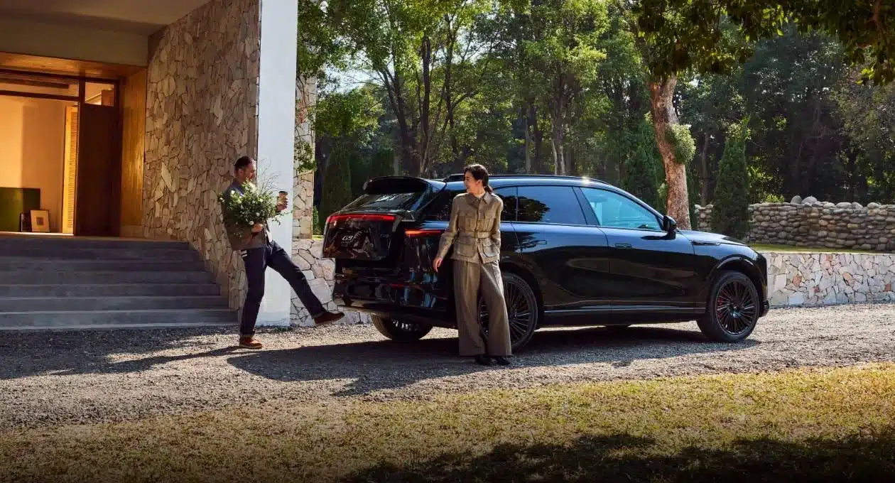 Zwei Personen vor einem schwarzen XPENG G9 SUV, geparkt vor einem modernen Haus mit geöffneter Heckklappe.