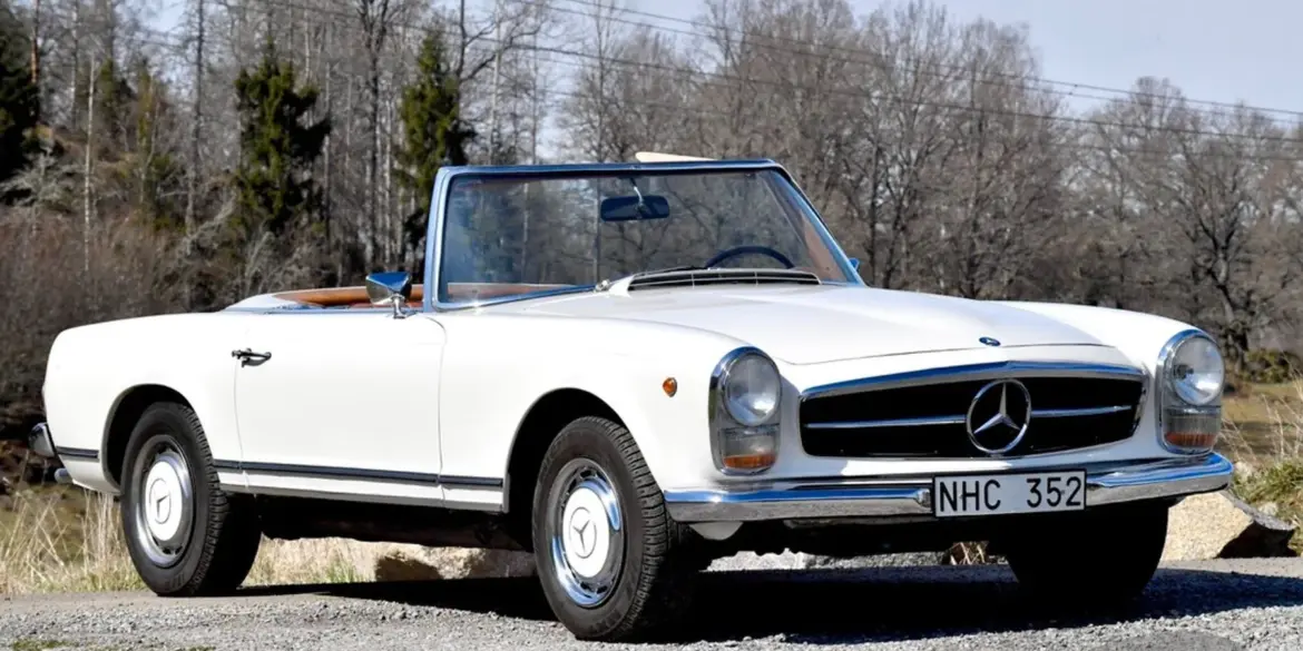 Seitenansicht eines weißen Mercedes-Benz 280 SL Pagode von 1968 mit geöffnetem Verdeck, aufgenommen bei Tageslicht