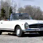 Seitenansicht eines weißen Mercedes-Benz 280 SL Pagode von 1968 mit geöffnetem Verdeck, aufgenommen bei Tageslicht