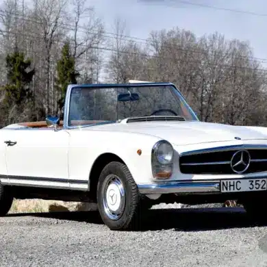 Seitenansicht eines weißen Mercedes-Benz 280 SL Pagode von 1968 mit geöffnetem Verdeck, aufgenommen bei Tageslicht