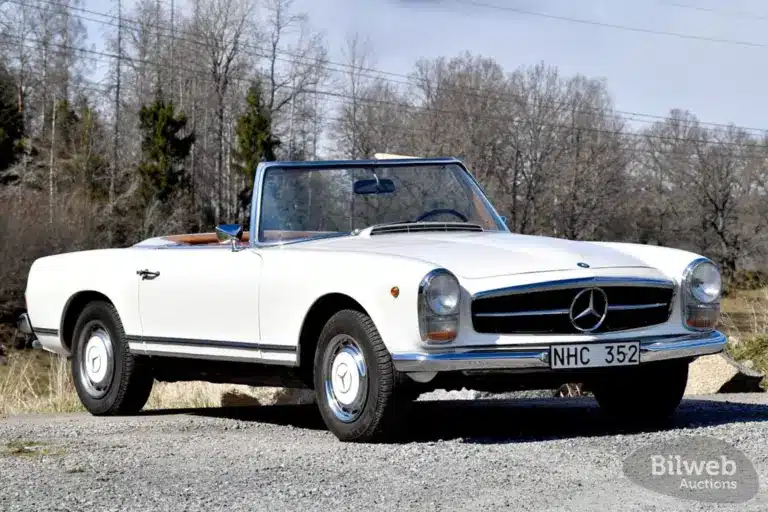 Seitenansicht eines weißen Mercedes-Benz 280 SL Pagode von 1968 mit geöffnetem Verdeck, aufgenommen bei Tageslicht
